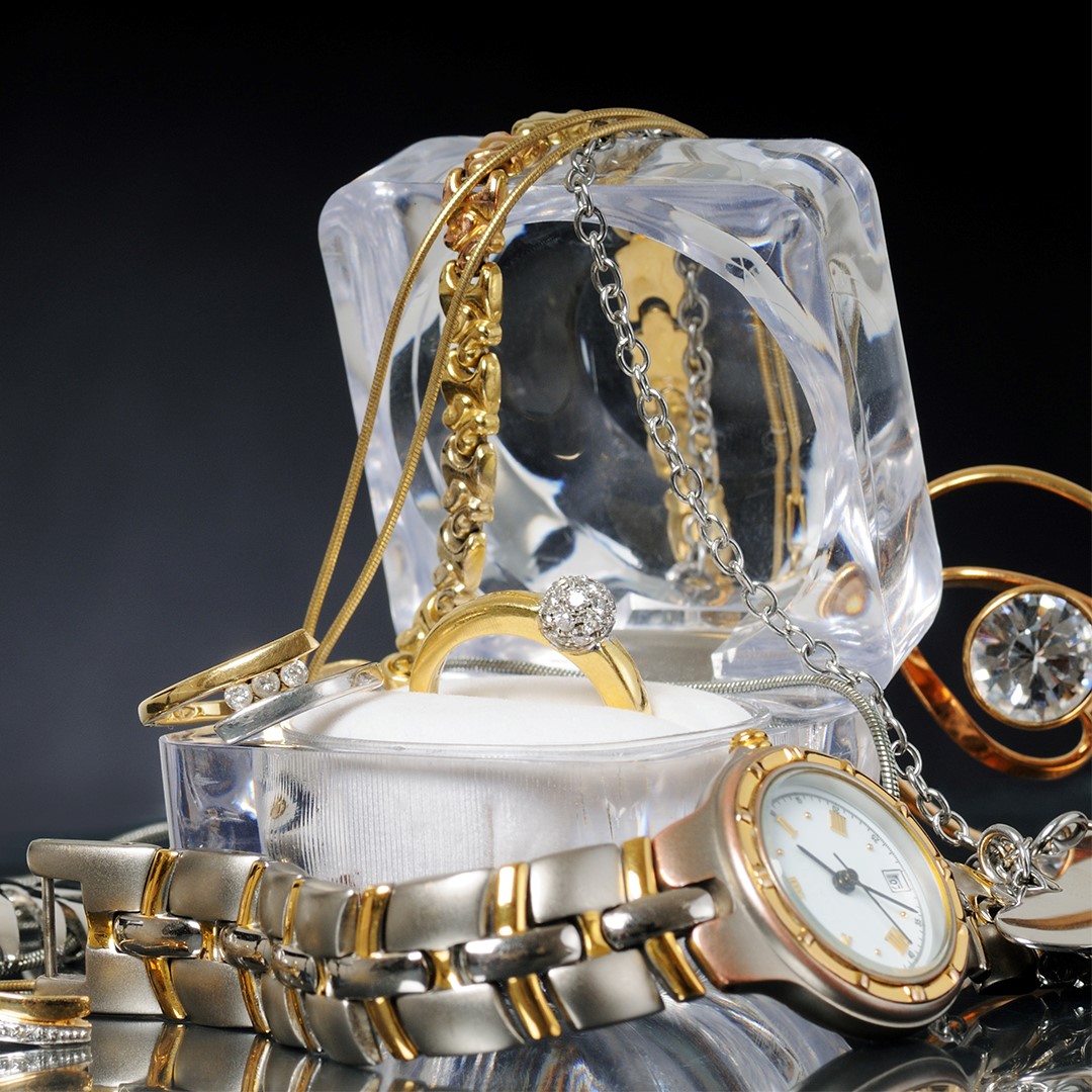 A ring in a transparent box surrounded by gold jewelry
